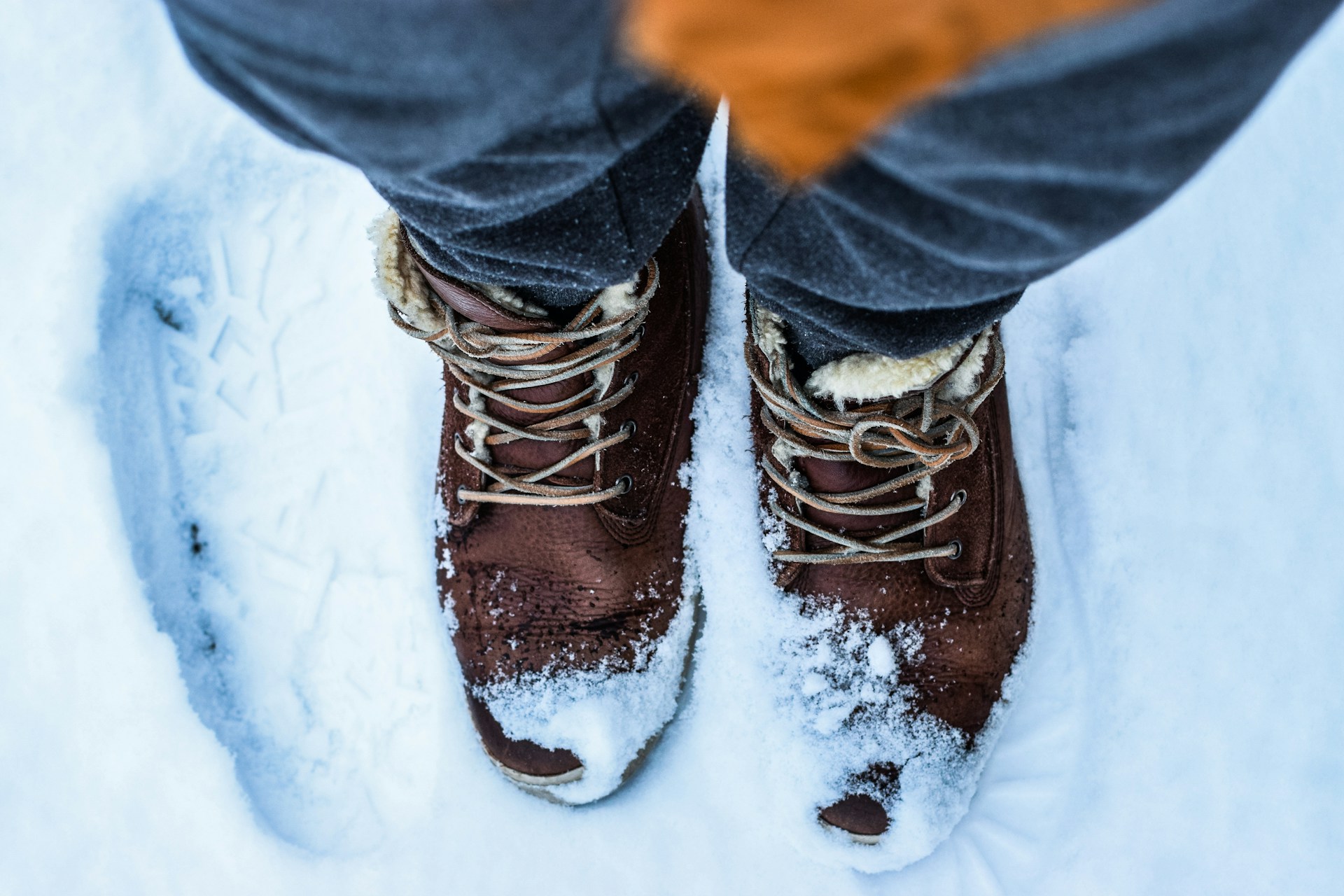 Closeup of man's feet wearing insulated winter boots in the snow.