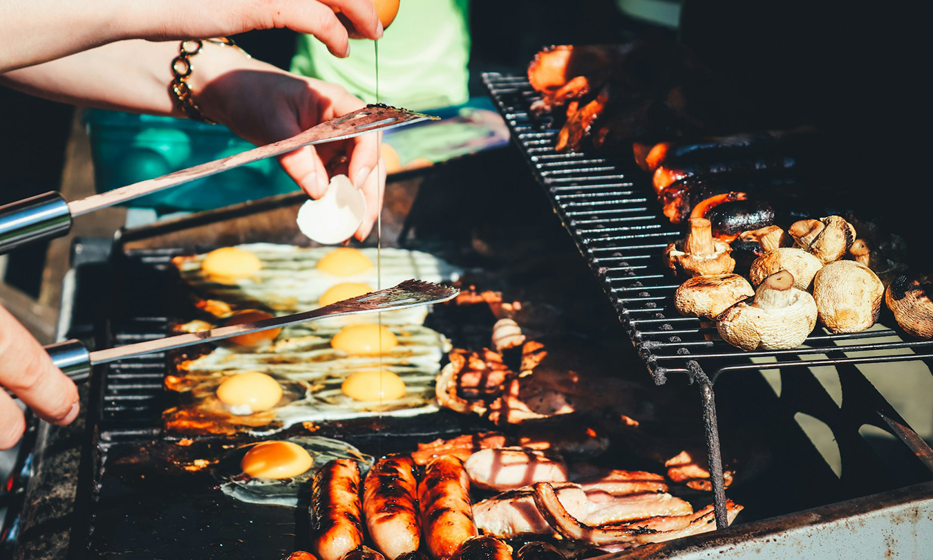 Tight closeup of meat and eggs on a grill.